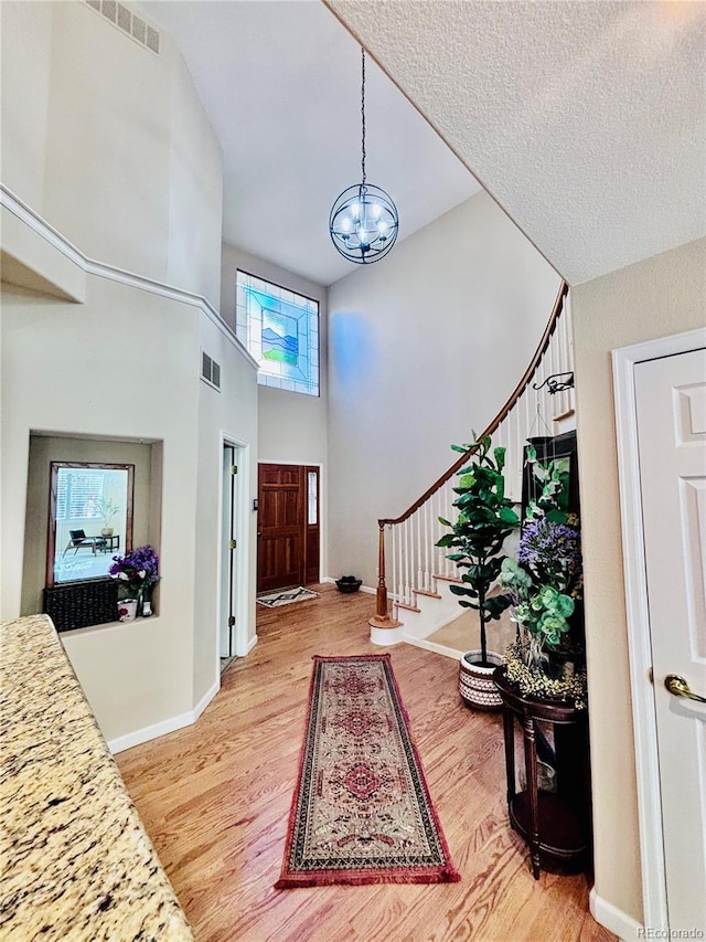 entryway with hardwood / wood-style flooring, a high ceiling, and a chandelier