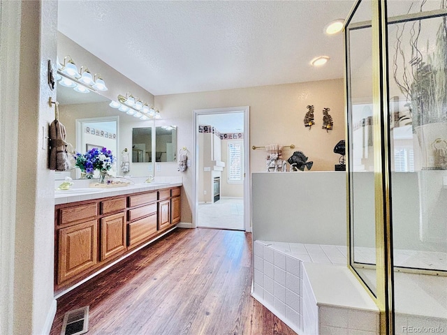 bathroom featuring vanity, wood-type flooring, a textured ceiling, and walk in shower