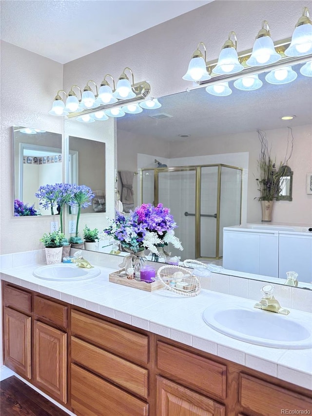 bathroom with vanity, a shower with door, and a textured ceiling