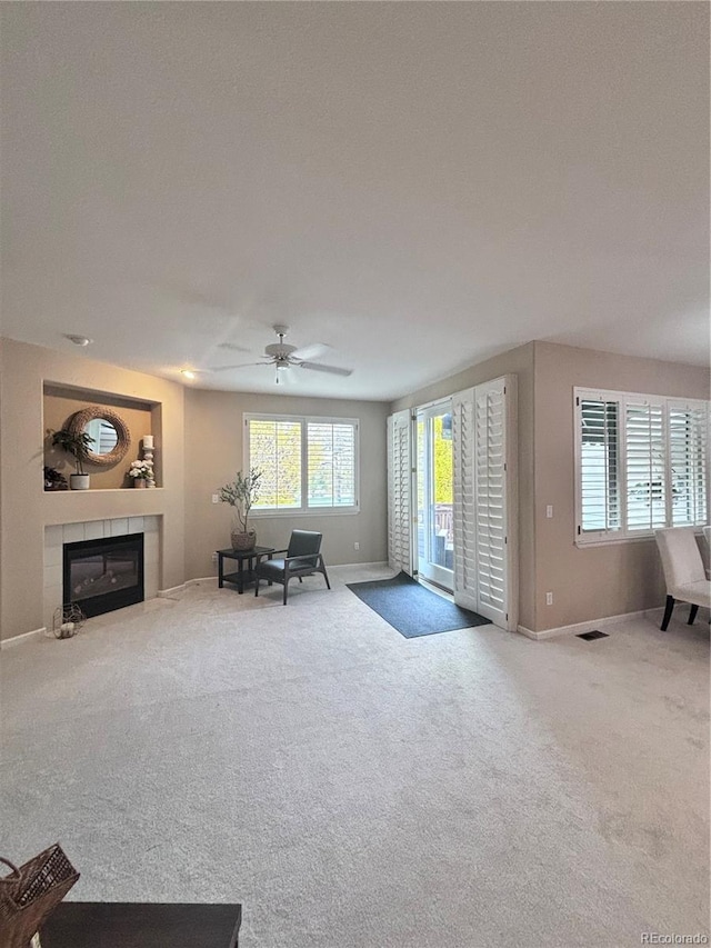 unfurnished living room featuring a tile fireplace, carpet floors, and ceiling fan