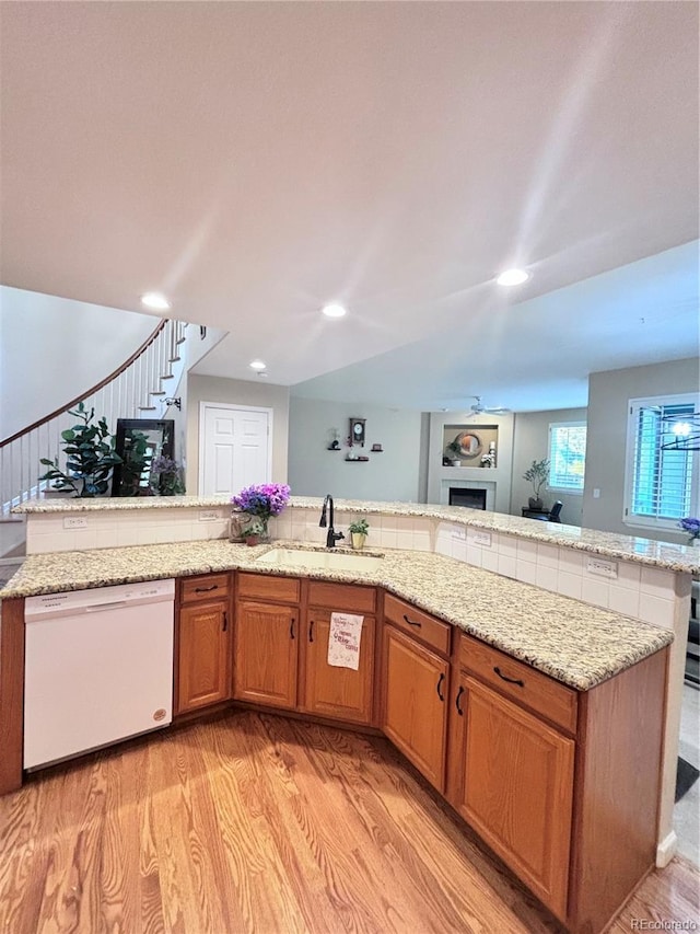 kitchen with light hardwood / wood-style floors, dishwasher, sink, and light stone countertops