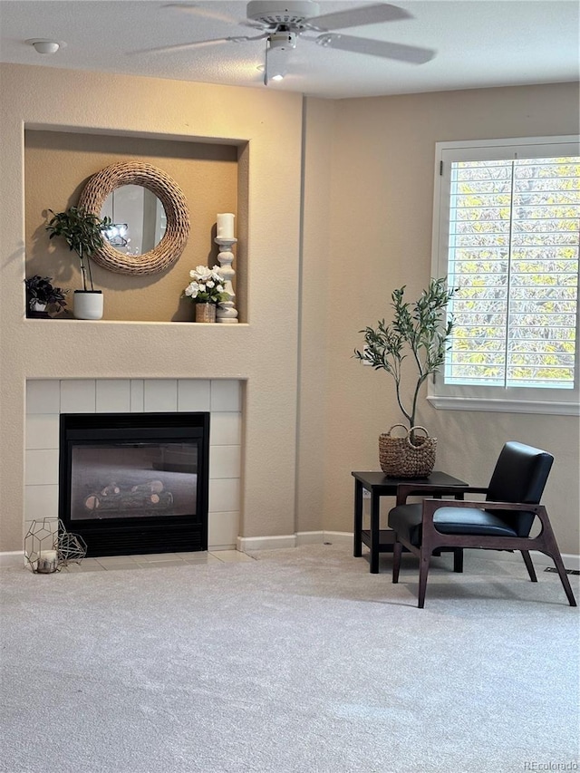 sitting room with carpet floors, a tile fireplace, and ceiling fan