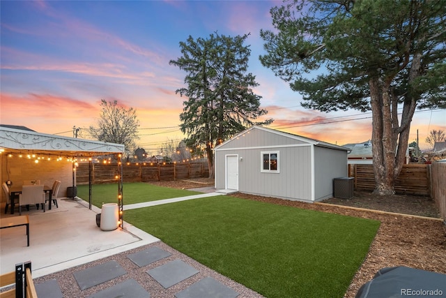 view of yard with a fenced backyard, an outdoor structure, and a patio area