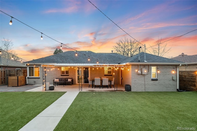 rear view of house featuring brick siding, a patio, fence, and a lawn