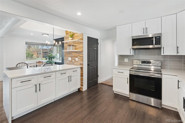 kitchen with backsplash, light countertops, appliances with stainless steel finishes, and dark wood finished floors