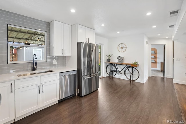 kitchen with light countertops, a sink, stainless steel appliances, visible vents, and dark wood-type flooring