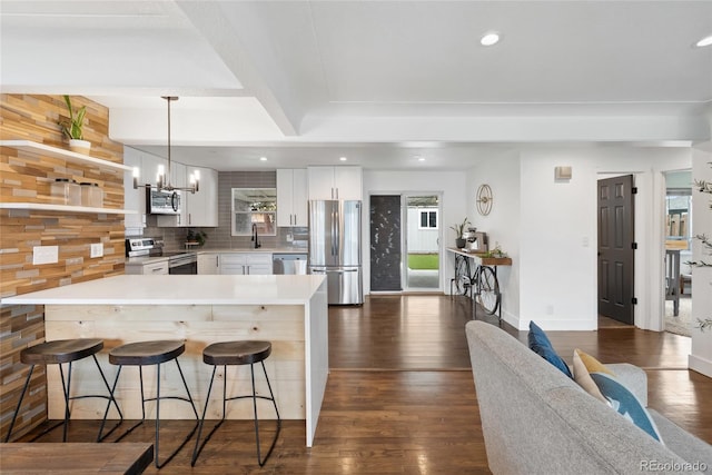 kitchen featuring dark wood-style flooring, tasteful backsplash, a kitchen bar, and stainless steel appliances