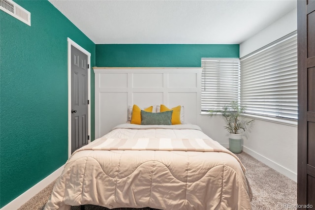 bedroom with baseboards, visible vents, a textured wall, and carpet flooring