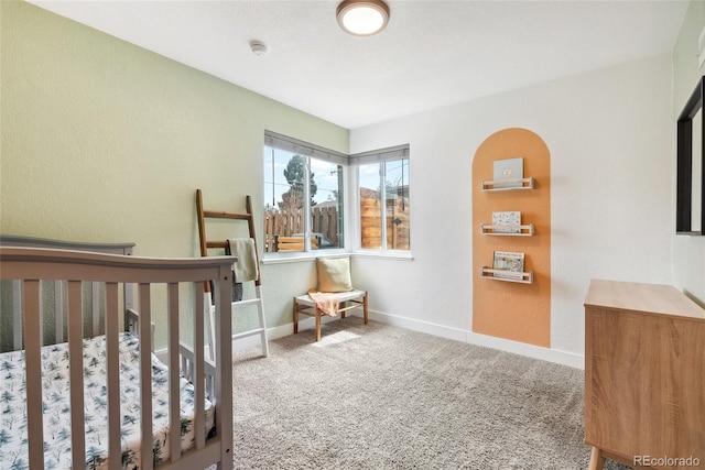 bedroom featuring baseboards, carpet flooring, and a textured wall