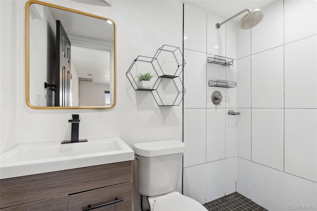 bathroom featuring a tile shower, toilet, and vanity