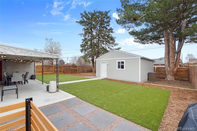 view of yard featuring an outbuilding, a fenced backyard, and a patio area