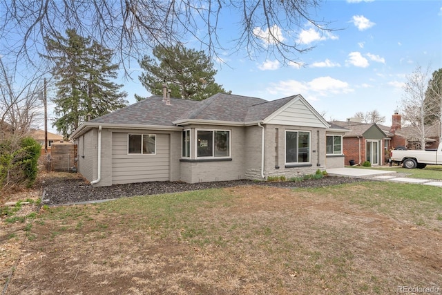 ranch-style home with roof with shingles, brick siding, fence, and a front lawn