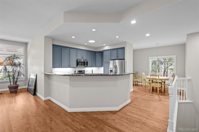 6900 W Grant Ranch Blvd Unit 88, Denver, CO 80123 - kitchen featuring stainless steel appliances, light wood-style flooring, dark stone counters, blue cabinetry, and recessed lighting