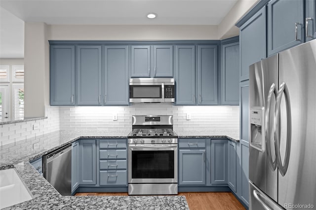 6900 W Grant Ranch Blvd Unit 88, Denver, CO 80123 - kitchen featuring appliances with stainless steel finishes, blue cabinets, light stone countertops, tasteful backsplash, and recessed lighting