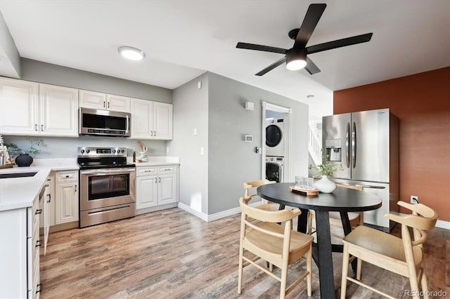 kitchen featuring stacked washer and clothes dryer, light countertops, appliances with stainless steel finishes, white cabinetry, and light wood-type flooring