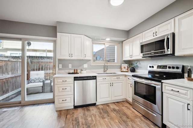 kitchen with a healthy amount of sunlight, appliances with stainless steel finishes, white cabinets, and a sink