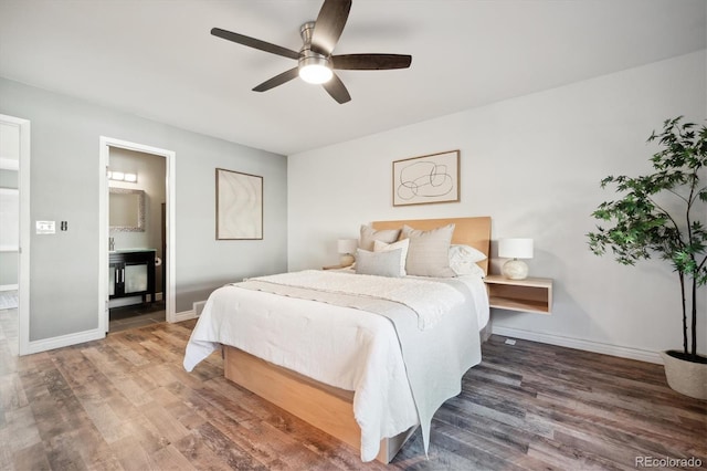 bedroom with a ceiling fan, ensuite bath, baseboards, and wood finished floors