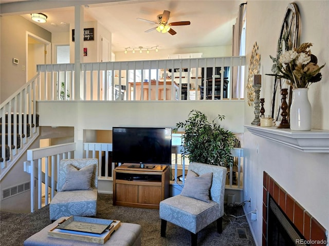 living room with carpet flooring, ceiling fan, a fireplace, and track lighting