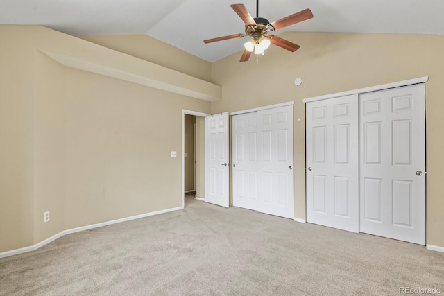 unfurnished bedroom featuring baseboards, carpet, multiple closets, and lofted ceiling