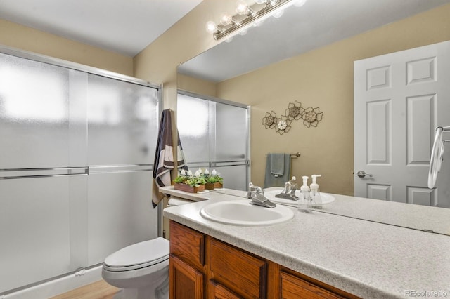 bathroom with vanity, a stall shower, toilet, and wood finished floors