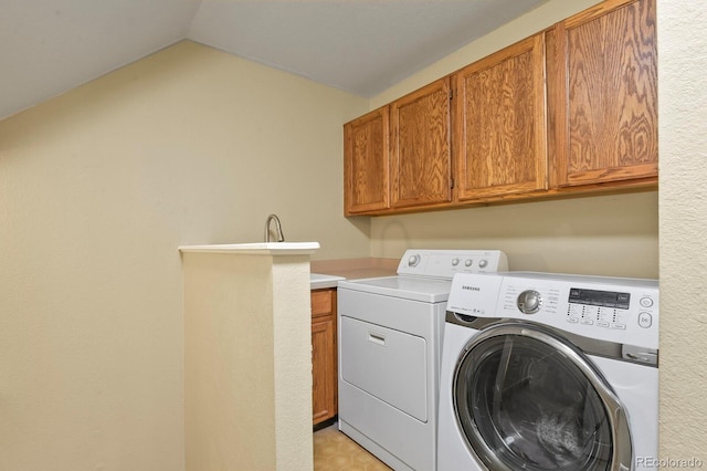 clothes washing area with separate washer and dryer and cabinet space