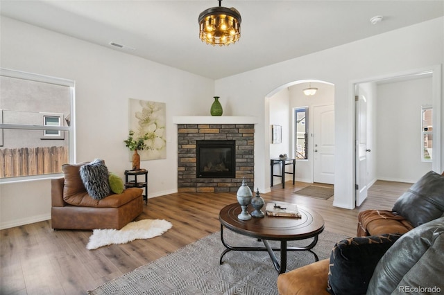 8339 Mosby Way, Colorado Springs, CO 80908 - living room featuring wood finished floors, arched walkways, and a stone fireplace