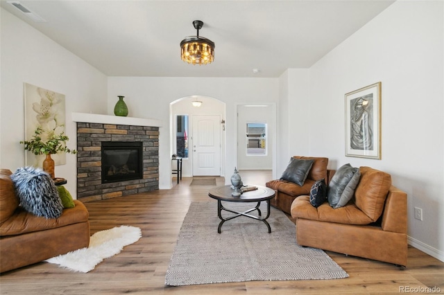 8339 Mosby Way, Colorado Springs, CO 80908 - living room featuring arched walkways, wood finished floors, and a stone fireplace