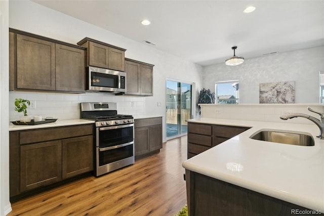 8339 Mosby Way, Colorado Springs, CO 80908 - kitchen with appliances with stainless steel finishes, light countertops, dark brown cabinets, wood finished floors, and decorative backsplash
