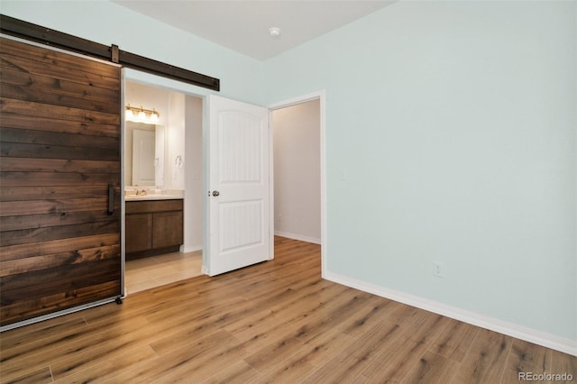 8339 Mosby Way, Colorado Springs, CO 80908 - unfurnished bedroom featuring light wood finished floors, a barn door, and ensuite bath