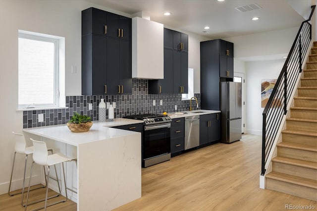 kitchen featuring light hardwood / wood-style flooring, tasteful backsplash, a breakfast bar, and appliances with stainless steel finishes