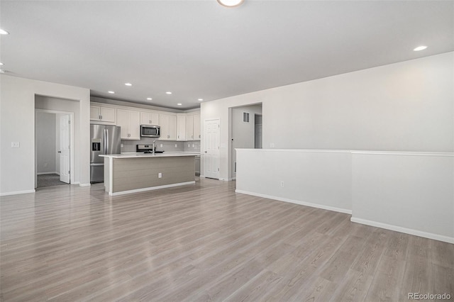 unfurnished living room featuring light hardwood / wood-style flooring and sink