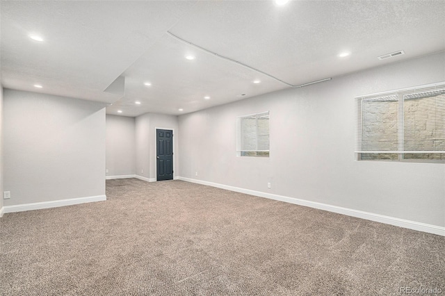 unfurnished room featuring carpet flooring, a wealth of natural light, and a textured ceiling