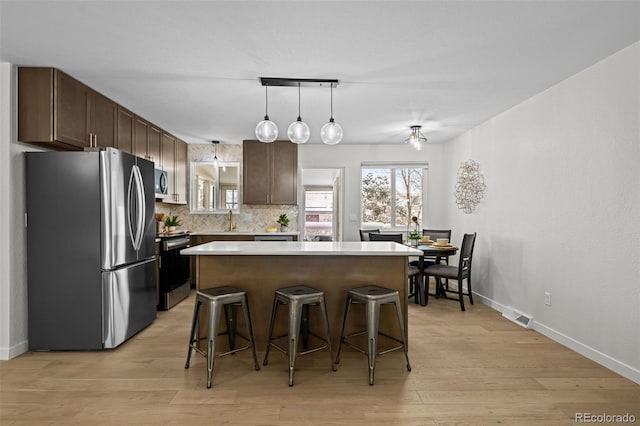 kitchen featuring a kitchen island, decorative backsplash, a kitchen bar, sink, and appliances with stainless steel finishes