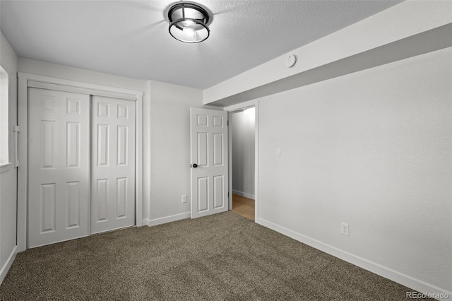 unfurnished bedroom with a textured ceiling, a closet, and dark colored carpet