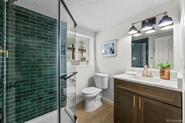 bathroom with a shower with shower door, hardwood / wood-style floors, toilet, and vanity