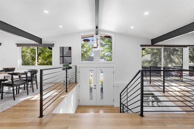 entryway with lofted ceiling with beams, a chandelier, and light hardwood / wood-style flooring