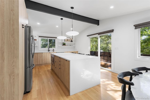 kitchen featuring hanging light fixtures, light hardwood / wood-style flooring, lofted ceiling with beams, a spacious island, and appliances with stainless steel finishes