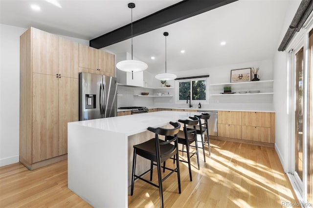 kitchen featuring light wood-type flooring, tasteful backsplash, stainless steel appliances, beam ceiling, and a kitchen island