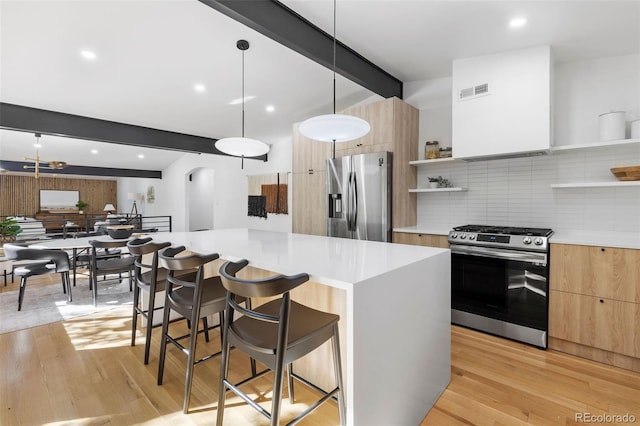 kitchen with a center island, stainless steel appliances, pendant lighting, light hardwood / wood-style floors, and a breakfast bar area