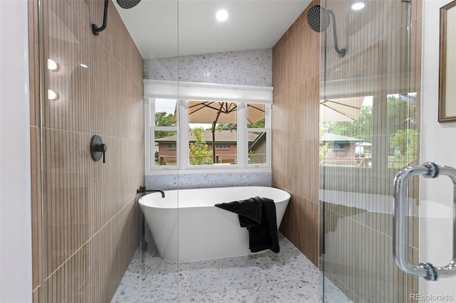 bathroom featuring shower with separate bathtub and tile walls