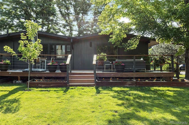 rear view of property featuring a lawn and a wooden deck