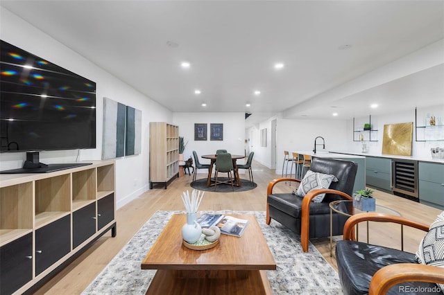 living room featuring light hardwood / wood-style floors, beverage cooler, and sink