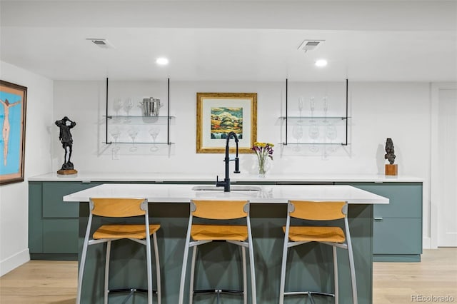 bar featuring light hardwood / wood-style flooring and sink