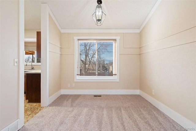 unfurnished room featuring ornamental molding, light colored carpet, and a healthy amount of sunlight