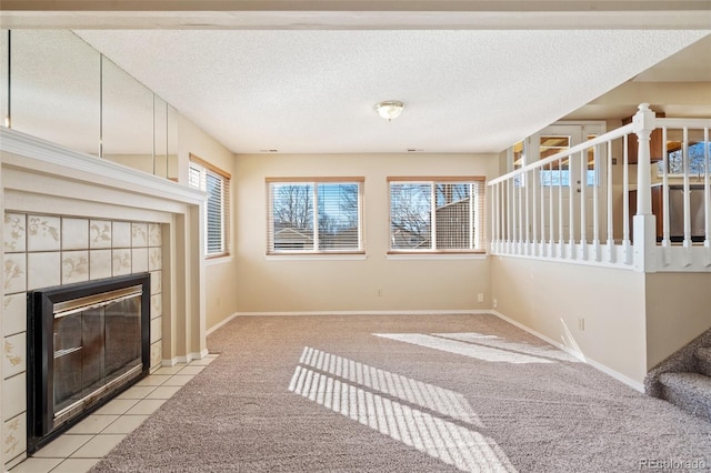 unfurnished living room featuring a tiled fireplace, light colored carpet, and a textured ceiling