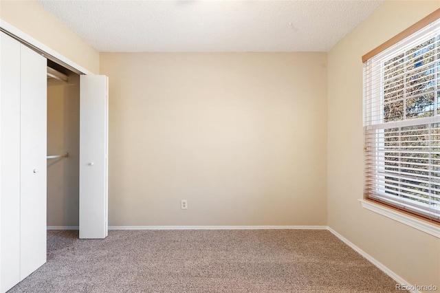 unfurnished bedroom featuring a closet, multiple windows, a textured ceiling, and carpet floors