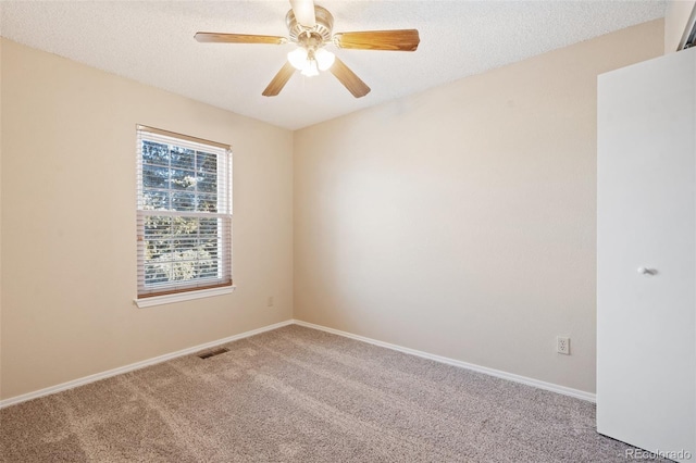 carpeted spare room featuring a textured ceiling and ceiling fan