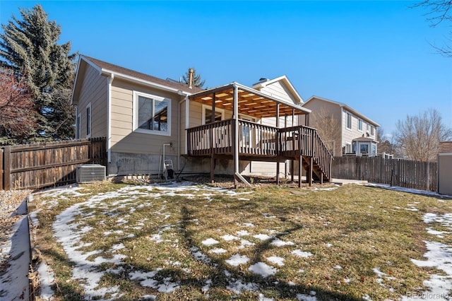 snow covered house with a lawn, a deck, and central AC unit