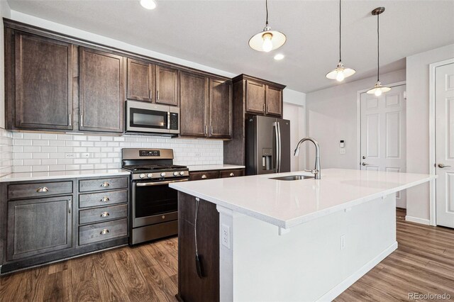 kitchen with a kitchen island with sink, stainless steel appliances, and light countertops