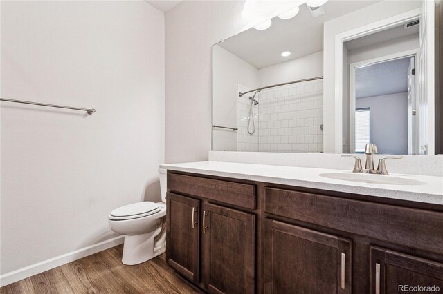 bathroom featuring baseboards, toilet, wood finished floors, walk in shower, and vanity